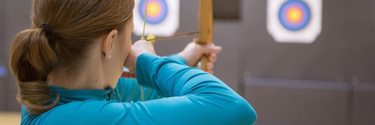 Junge Frau schießt mit Pfeil und Bogen