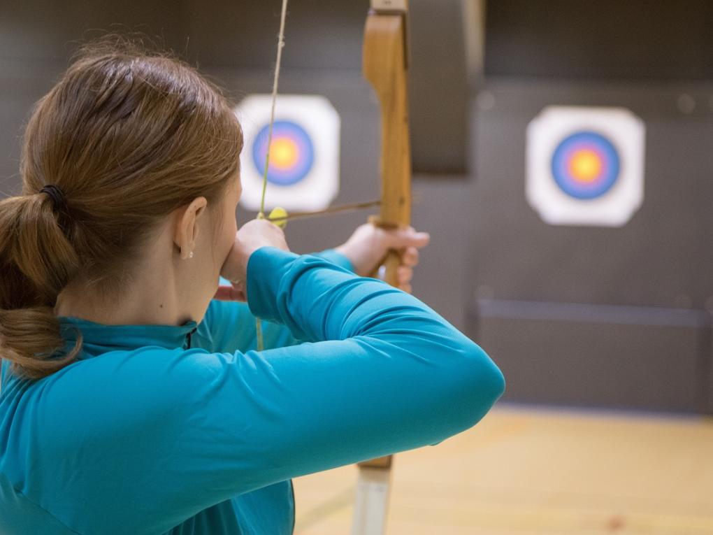 Junge Frau schießt mit Pfeil und Bogen